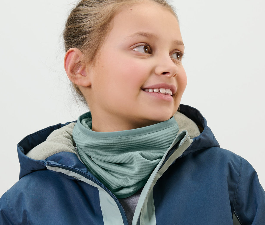 Mädchen trägt ein Kinder-Multifunktionstuch und eine blaue Jacke.