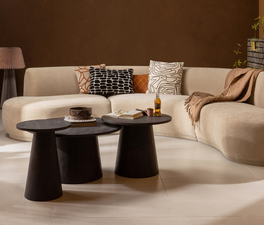 Wohnzimmer mit beigem Sofa, braunen Kissen und zwei dunkelbraunen Woood Maan Couchtischen.
