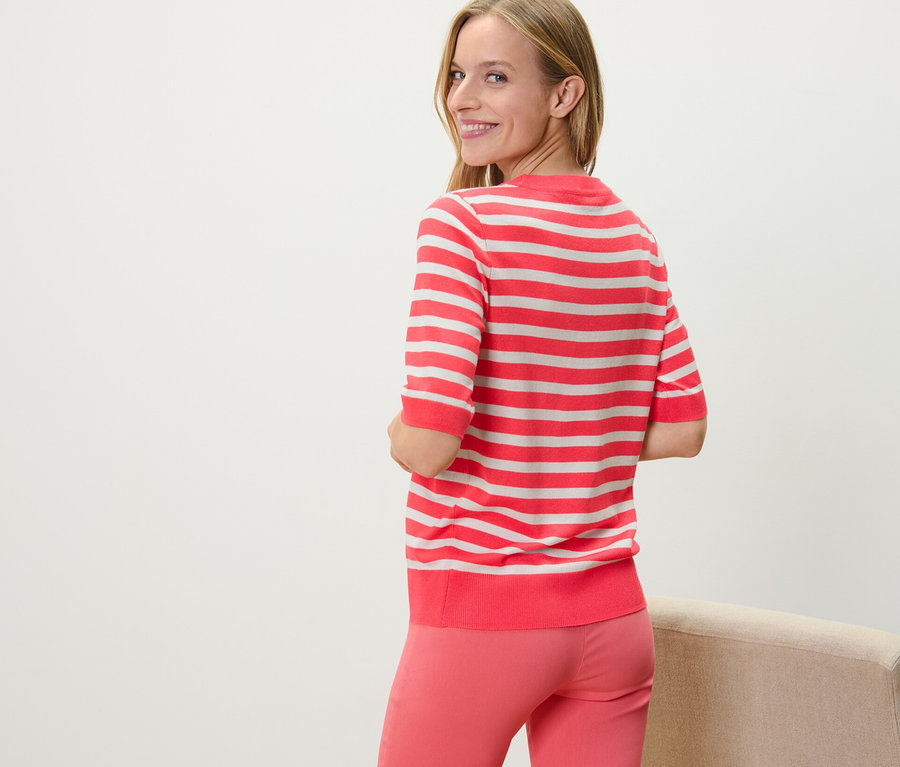 Frau blickt über die Schulter und trägt einen gestreiften Feinstrickpullover.