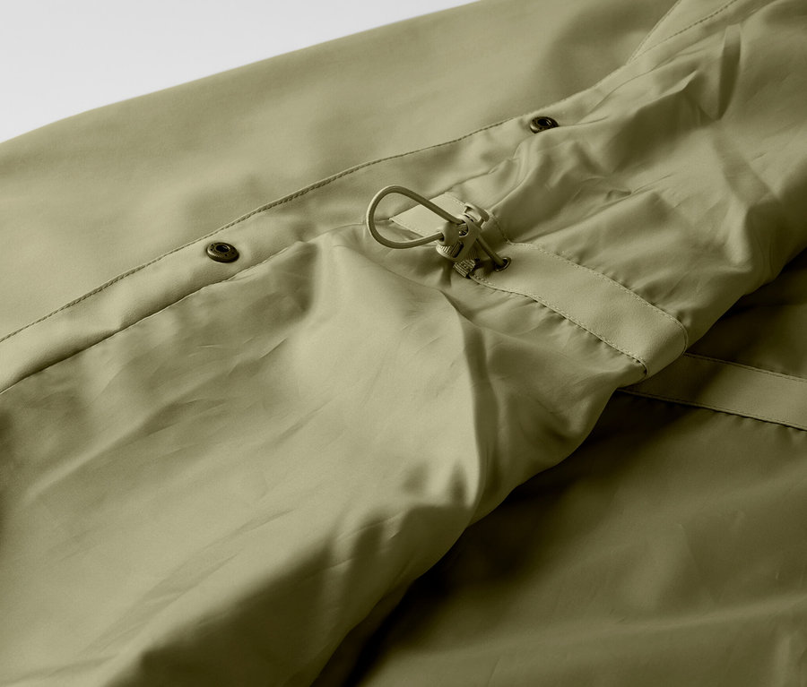 Detailaufnahme eines khaki Regenmantels mit Knöpfen und Kordelzug.
