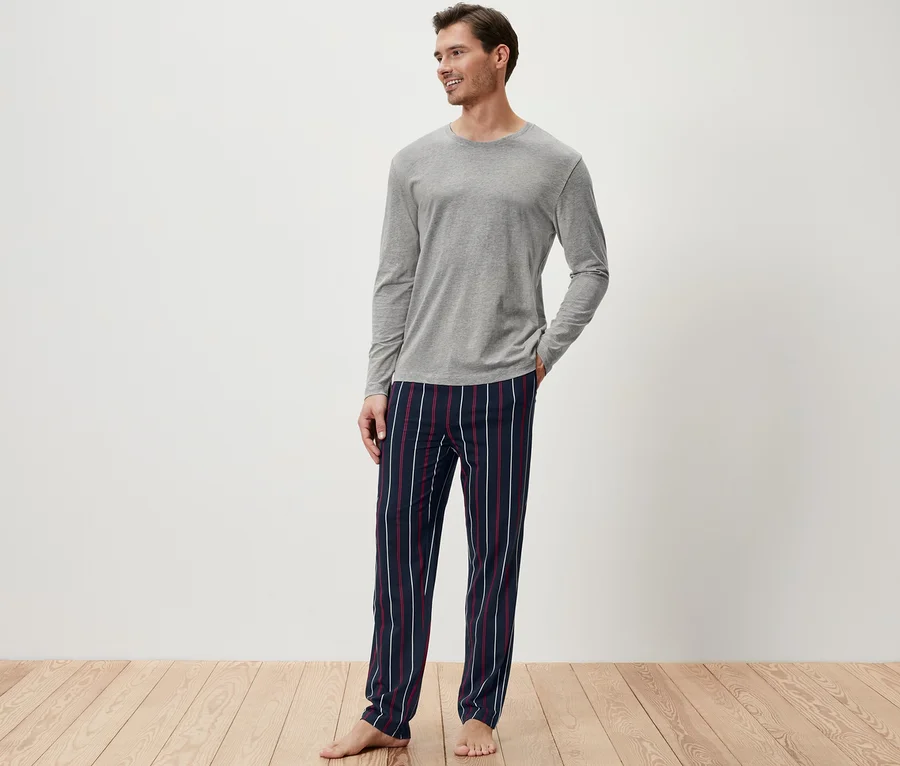Mann im grauen Pyjamaoberteil und gestreifter Pyjamahose.