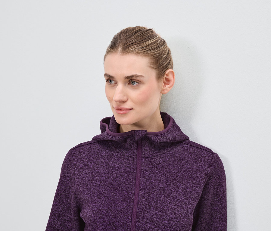 Porträt einer blonden Frau in einem lila Kapuzenpullover.