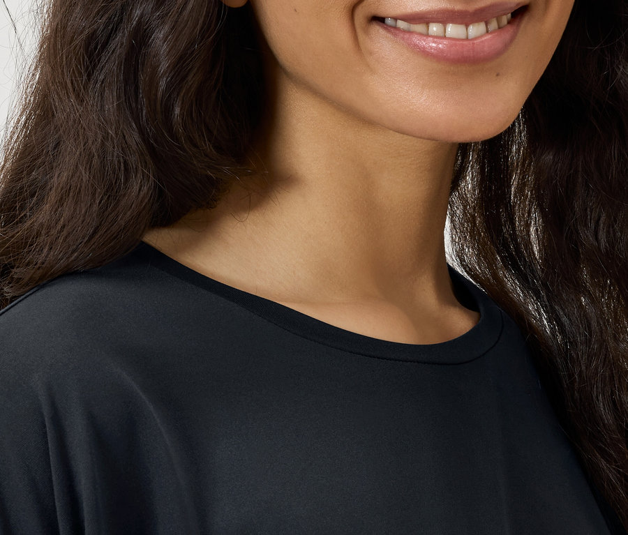 Detailaufnahme vom Gesicht einer Frau mit dunklem, welligem Haar und einem schwarzen T-Shirt.