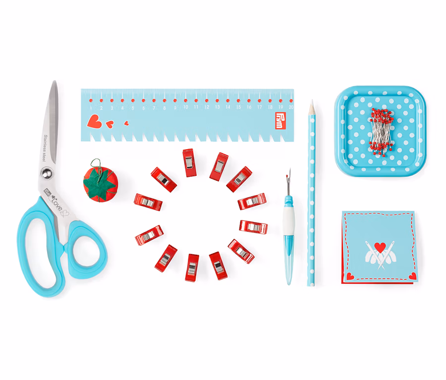 Schere, Stecknadeln, Maßband, Nahttrenner, Klemmen und andere Utensilien aus dem Prym Starter-Set Nähen »Love«.