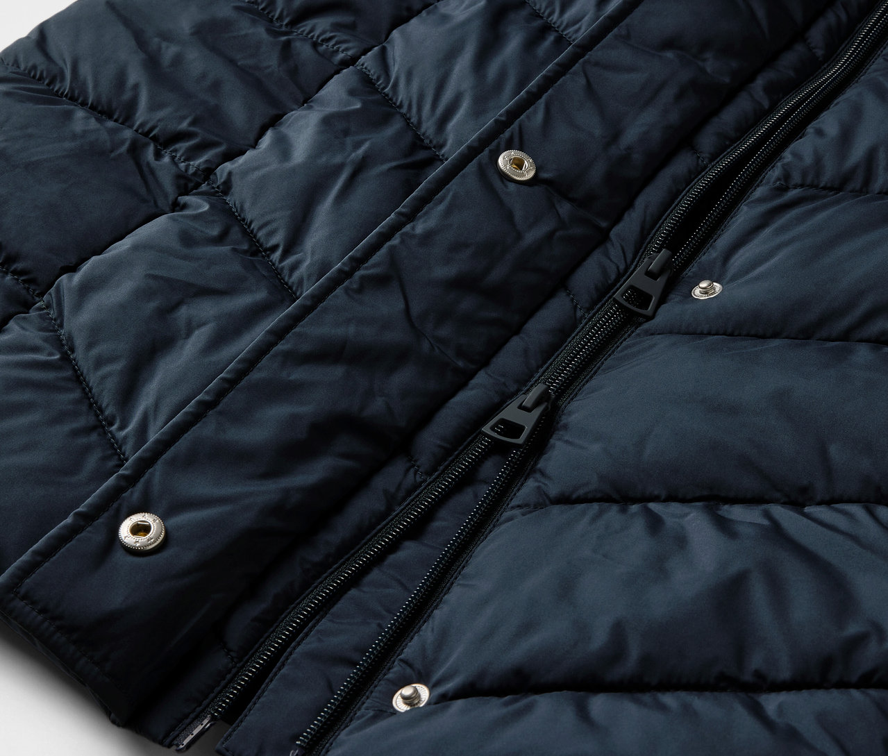 Detailansicht eines dunkelblauen Steppmantels mit Kapuze.