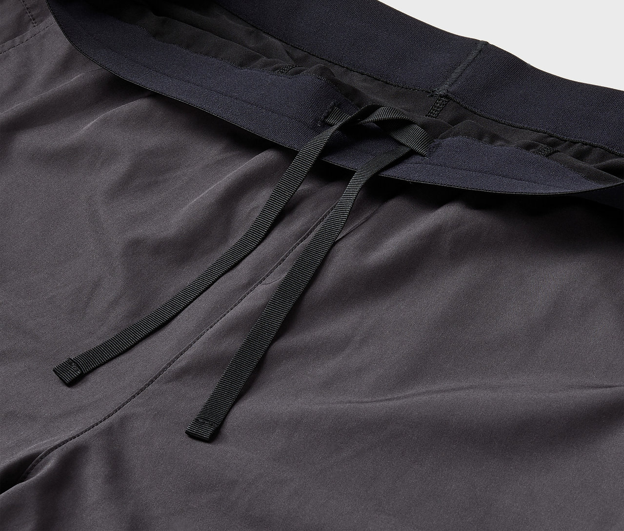 Detail einer grauen Trainingshose mit schwarzem Gummibund und Kordel.