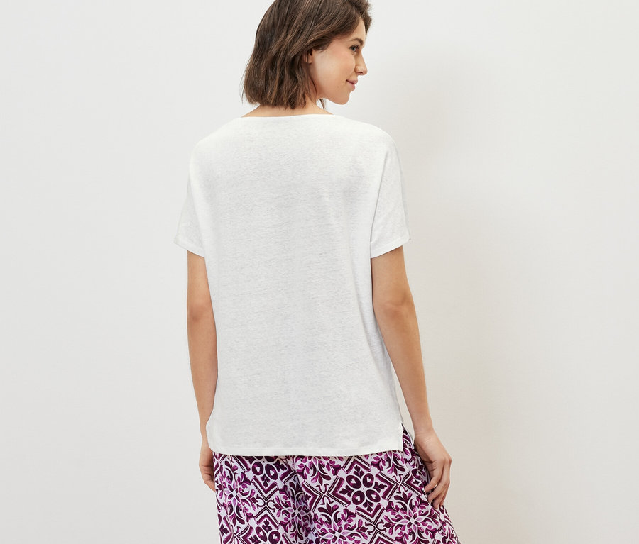 Frau von hinten trägt ein weißes Shirt aus Leinenmix und eine gemusterte Hose.