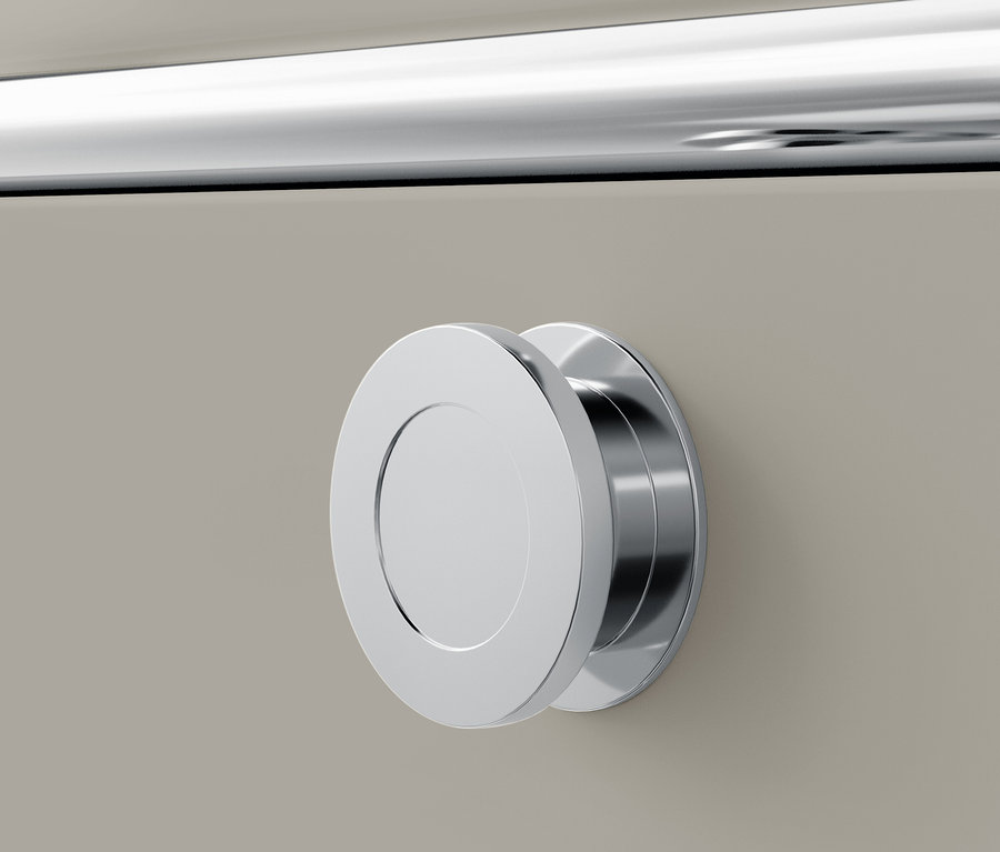 Detail eines verchromten, runden Griffs an einer beigen Schublade.