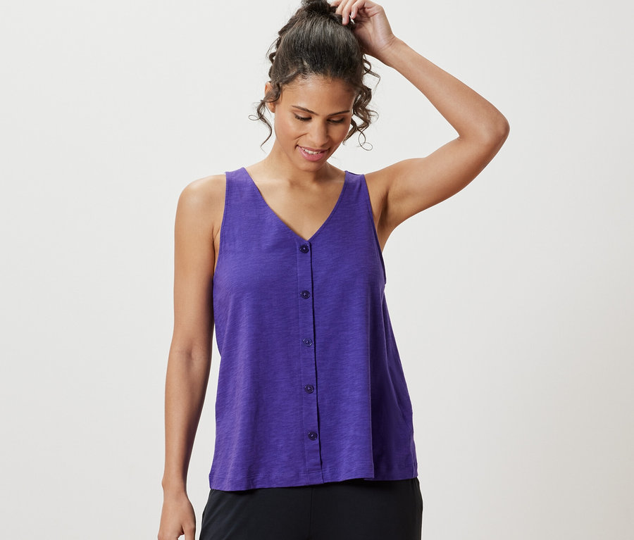 Frau richtet ihre Haare und trägt ein lila Top aus Modalmix.