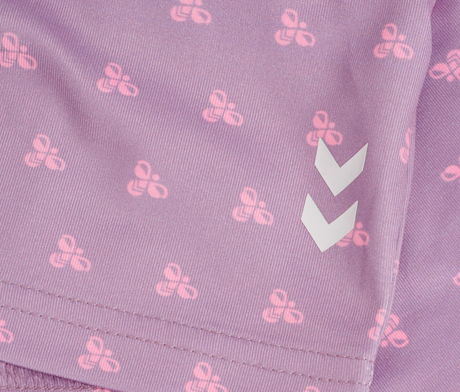 Nahaufnahme eines lilafarbenen Stoffes mit einem Muster aus rosa Schleifen und einem weißen Winkel.