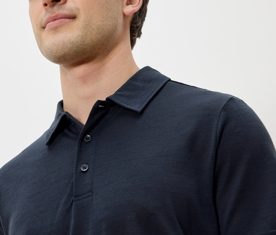 Nahaufnahme eines Mannes, der ein dunkelblaues Poloshirt trägt.