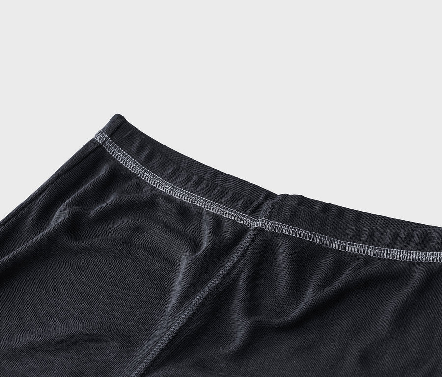 Nahaufnahme von dunkelgrauem Rippstoff mit weißen Nähten, die einen elastischen Bund und eine vertikale Naht hervorheben.