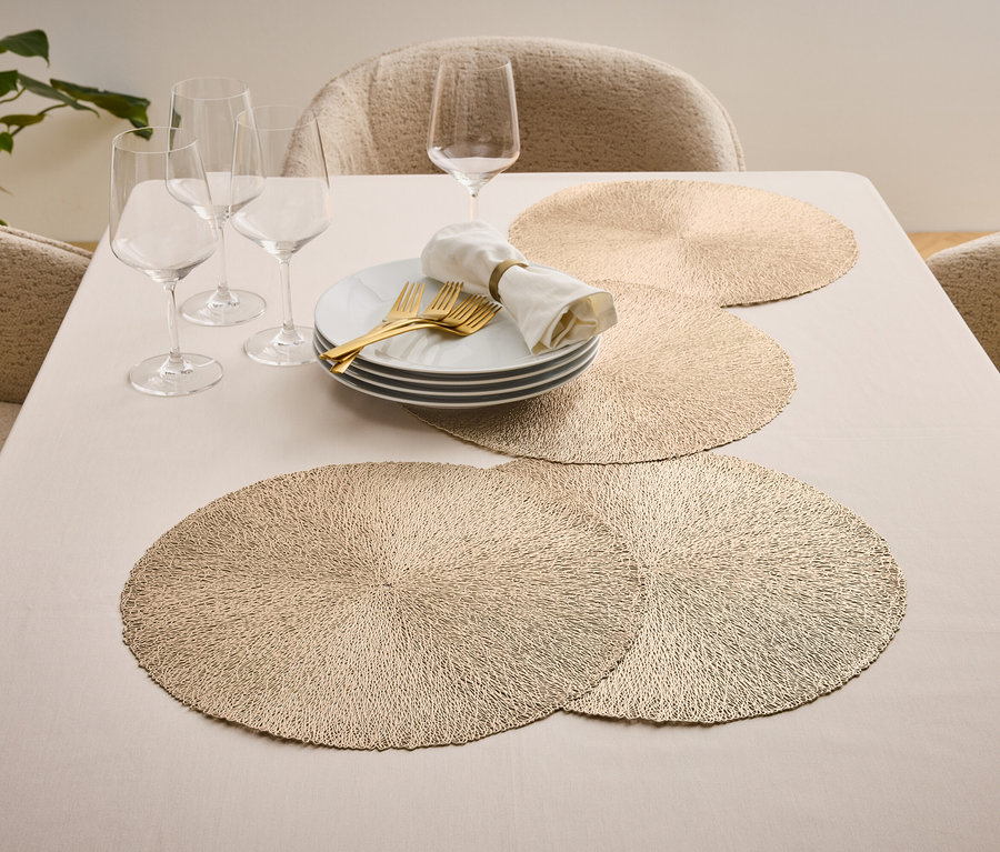 Gedeckter Tisch mit Tellern, goldenem Besteck, Gläsern und Tischsets.