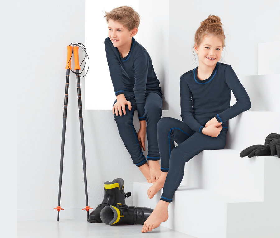Ein Junge und ein Mädchen sitzen auf einer weißen Treppe und tragen Funktionsunterwäsche.