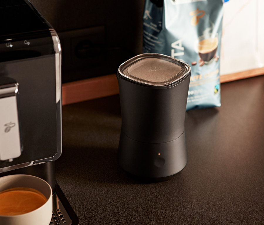 Kaffeemaschine neben einem schwarzen, elektrischen Milchaufschäumer.