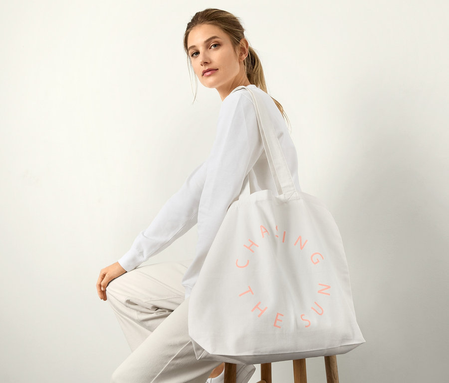 Frau sitzt auf einem Hocker mit einem Canvas-Shopper über ihrer Schulter.