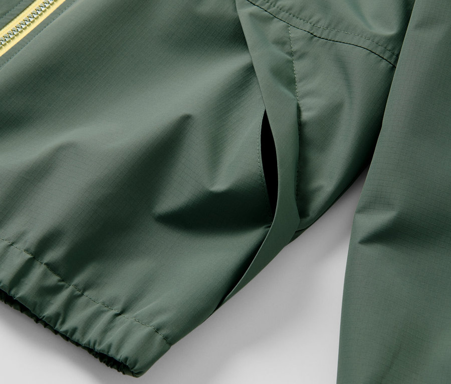 Detailansicht einer grünen Kinder-Sport-Funktionsjacke mit gelbem Reißverschluss.