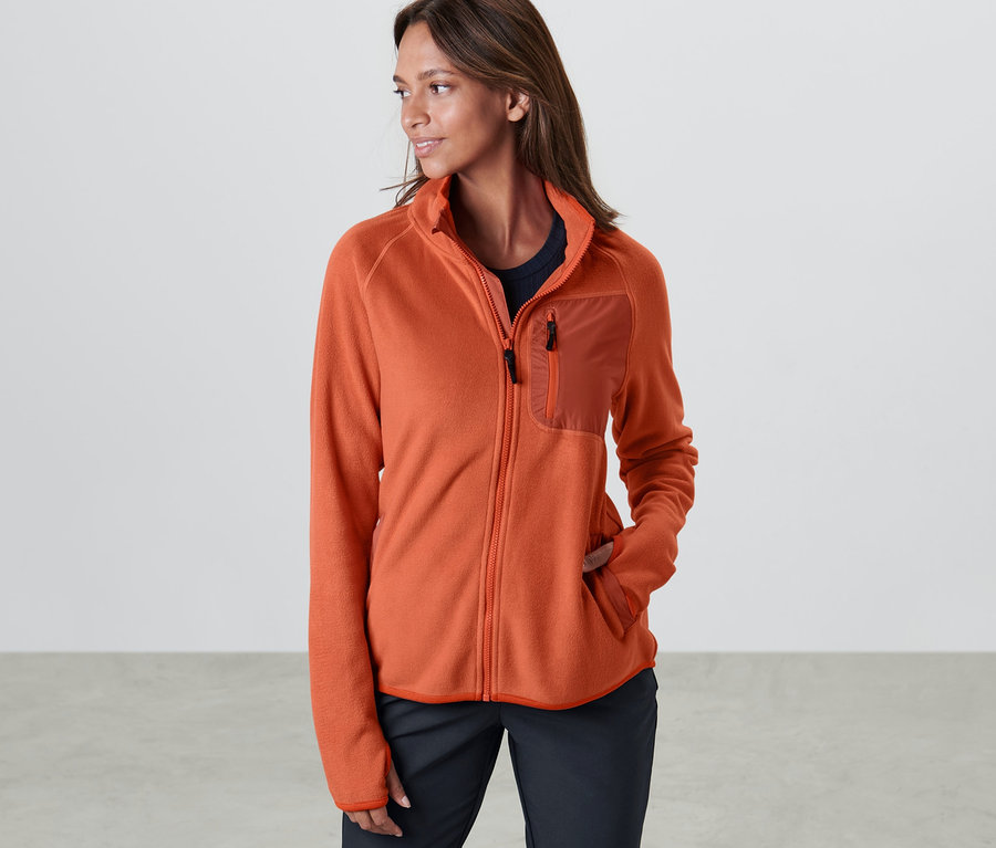 Frau posiert in orangefarbener Fleecejacke.