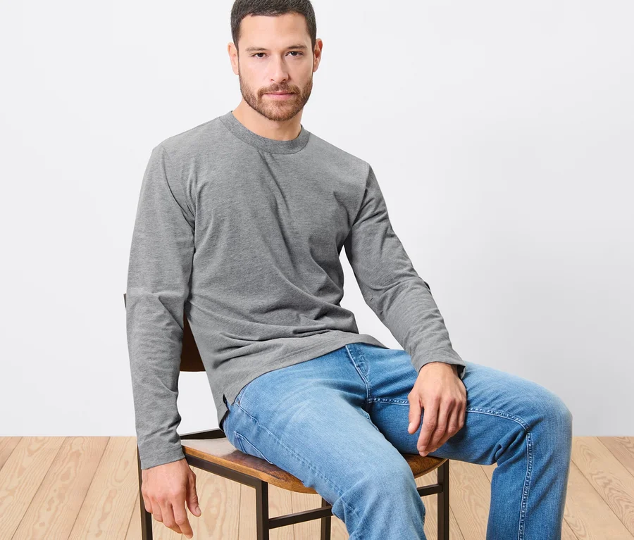Mann sitzt auf Stuhl mit grauem 2 Langarm-Shirts.