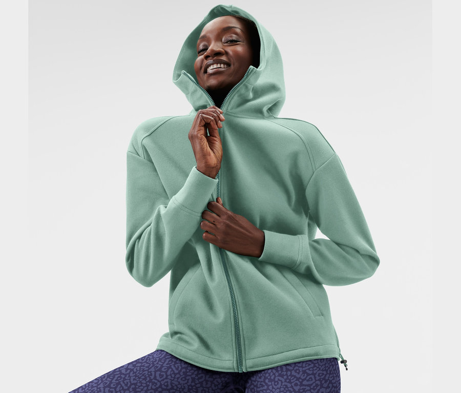 Frau posiert in mintfarbener Kapuzen-Sweatjacke.