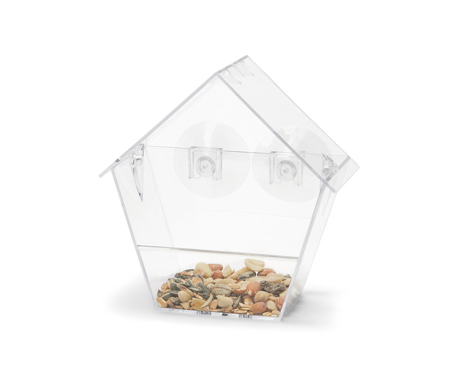 Ein transparentes Fenster-Vogelfutterhaus gefüllt mit Körnern.