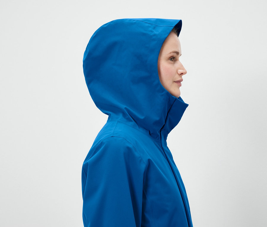 Profil einer Frau in einer blauen Jacke mit Kapuze.