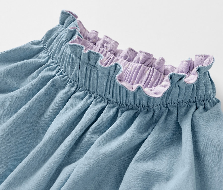 Detailansicht eines Kinder-Denim-Wenderocks mit lila Rüschenbund.