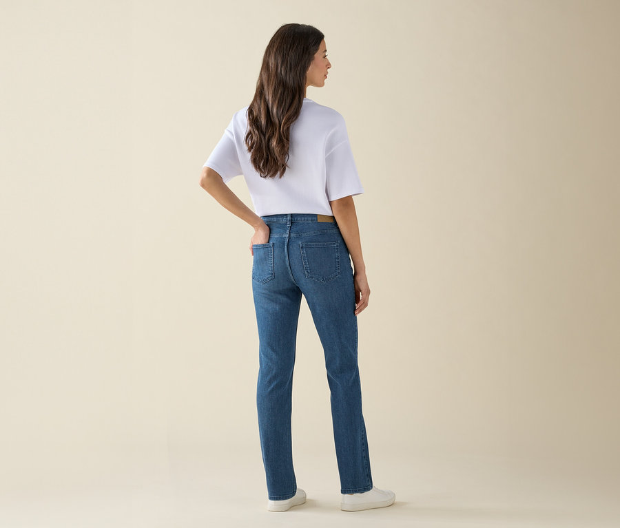 Frau mit dem Rücken zur Kamera trägt Jeans, T-Shirt und Turnschuhe.