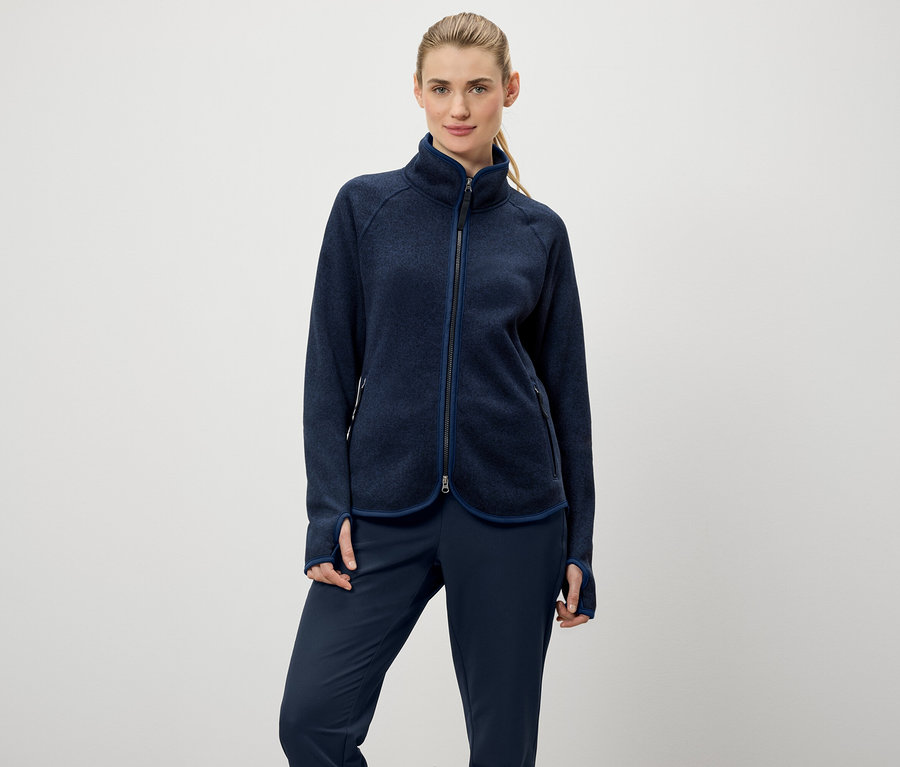 Frau trägt eine marineblaue Fleecejacke mit Reißverschluss und marineblaue Hosen.