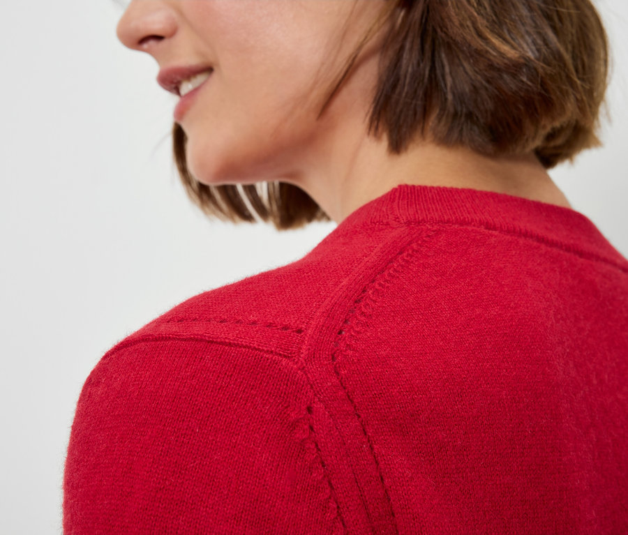 Detailaufnahme einer Frau mit kurzem braunen Haaren in einem roten Pullover.