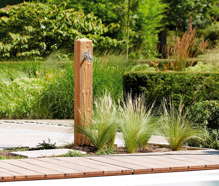 Eine Garantia Wassersäule, Wood, mit Wasserhahn steht neben einem Pool und Ziergras.