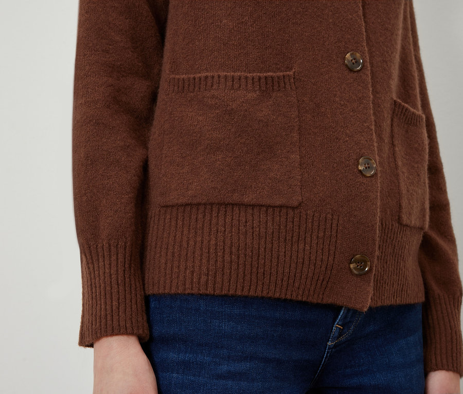 Detailaufnahme einer braunen Strickjacke mit Taschen und Knöpfen.