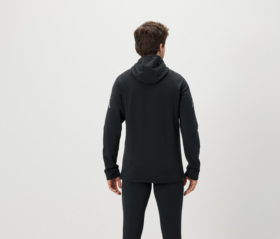 Ein Mann mit dem Rücken zur Kamera trägt einen schwarzen Kapuzenpullover und eine schwarze Hose.
