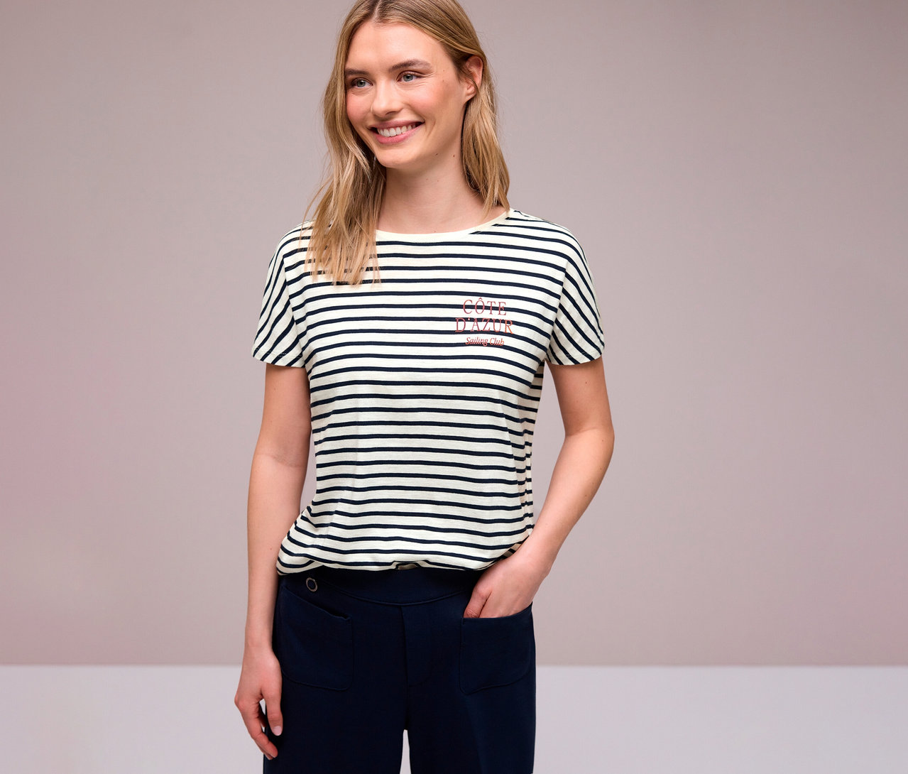 Frau mit blonden Haaren trägt ein navy-weißes Street One T-Shirt mit Streifen und marineblaue Hosen.