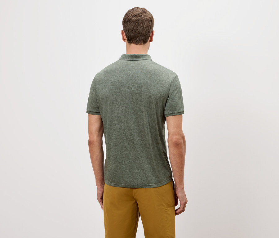 Rückansicht eines Mannes mit grünem Poloshirt und goldfarbenen Shorts vor einem weißen Hintergrund.