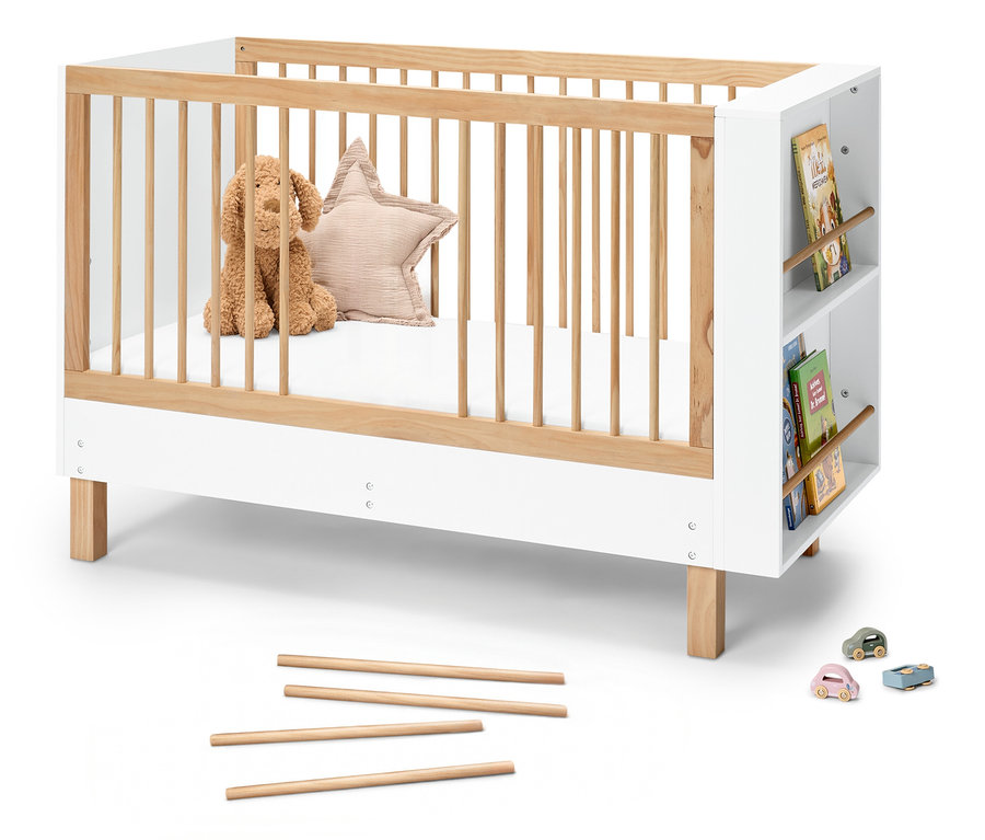 Das Babybett »Leira« mit integriertem Bücherregal zeigt ein Stofftier und ein Sternkissen im Bett. Drei Spielzeugautos stehen davor.