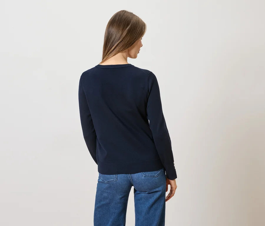 Rückansicht einer Frau mit langen braunen Haaren, die einen dunkelblauen Pullover und Jeans trägt.