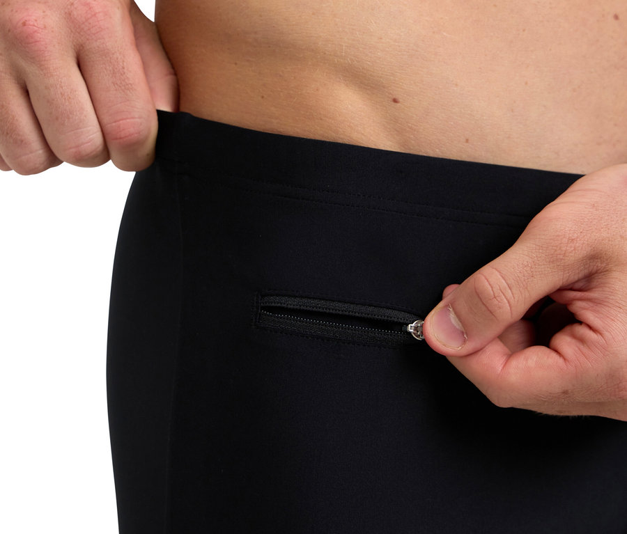 Mann öffnet den Reißverschluss einer schwarzen Hose.