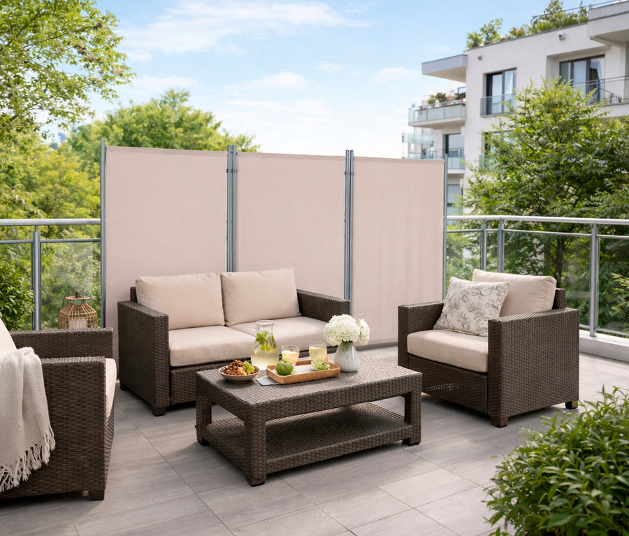 Auf einer Terrasse stehen Rattansessel und ein Tisch vor einer beigen, dreiteiligen Leco Stellwand.