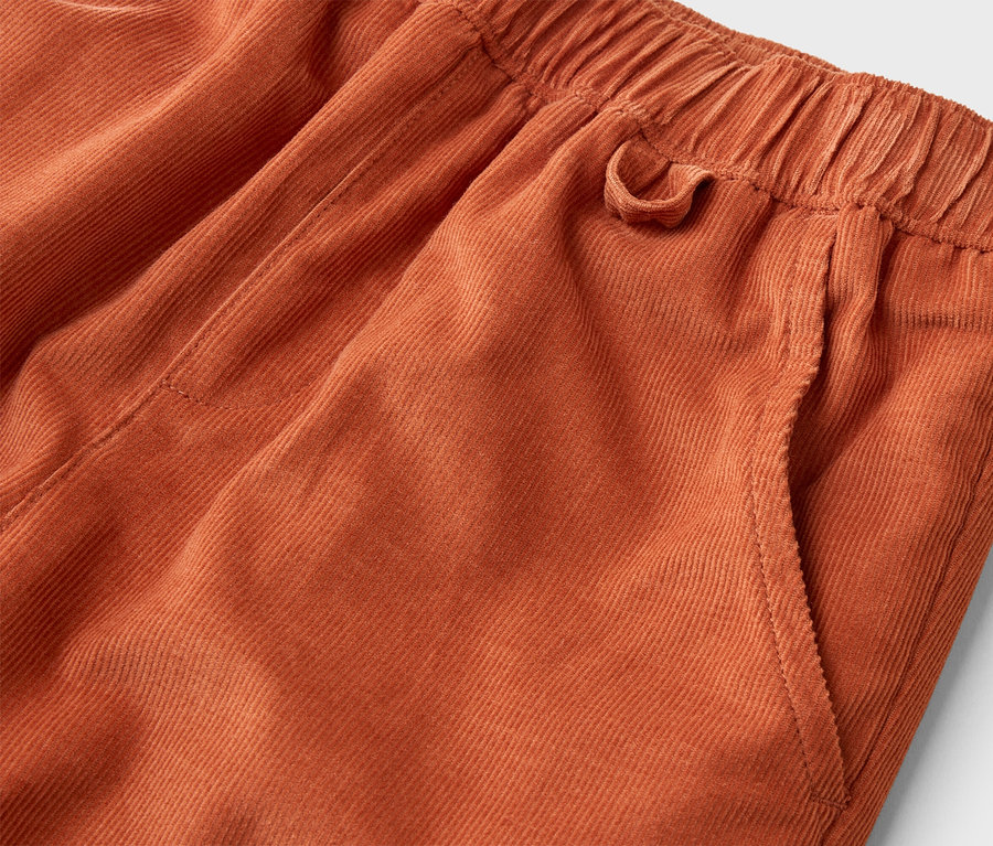 Nahaufnahme einer orangefarbenen Kordhose mit Gummibund und Seitentasche.