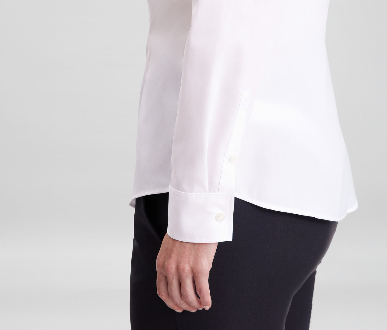 Eine Person trägt eine weiße, bügelfreie Seidensticker Slim Fit Bluse und schwarze Hose, der Ärmel mit Manschette ist sichtbar.