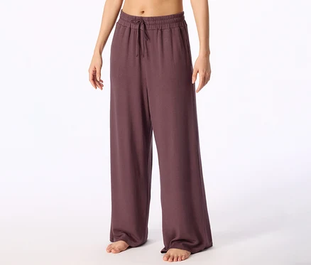 Barfüßige Person trägt dunkelviolette weite Hose mit Kordelzug in der Taille.