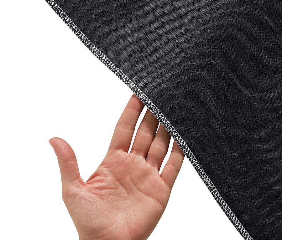 Hand hält Rand von schwarzem Stoff mit weißem Overlock-Stich.