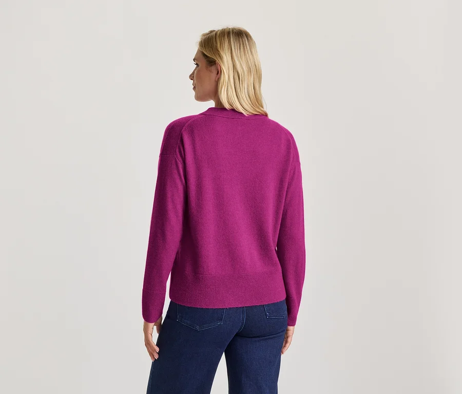 Frau von hinten in einem magentafarbenen Pullover und dunkelblauen Jeans.