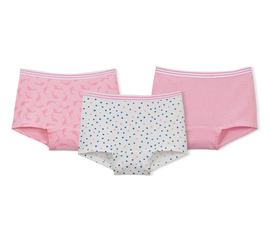 Drei Mädchen-Pantys liegen auf einem weißen Hintergrund: eine rosa mit Delfinen, eine weiße mit bunten Punkten und eine rosa gestreifte.
