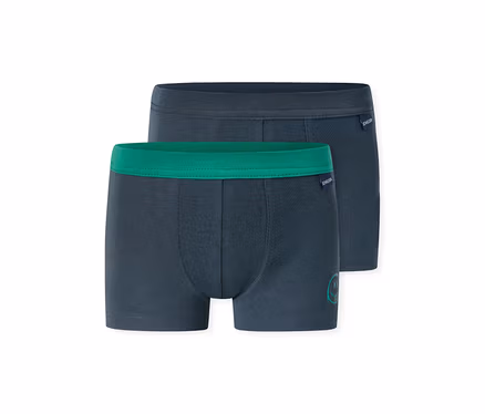 Zwei dunkelblaue Jungen-Boxershorts, eine mit grünem Bund und kleinem grünem Aufdruck, die andere mit dunkelblauem Bund. Beide haben das SCHIESSER-Logo.