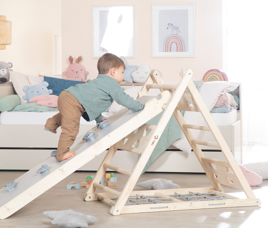Ein Junge klettert auf ein roba Kletterdreieck im Kinderzimmer.