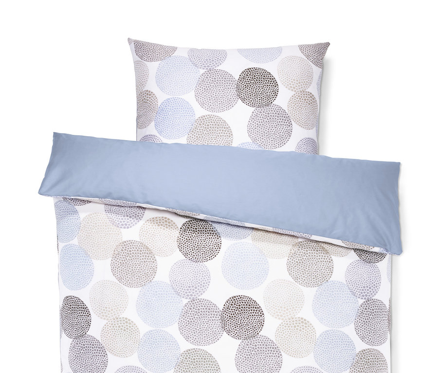 Auf einem weißen Hintergrund liegt eine Satin-Wendebettwäsche in Normalgröße mit blauem Rand und einem Muster aus gepunkteten Kreisen.