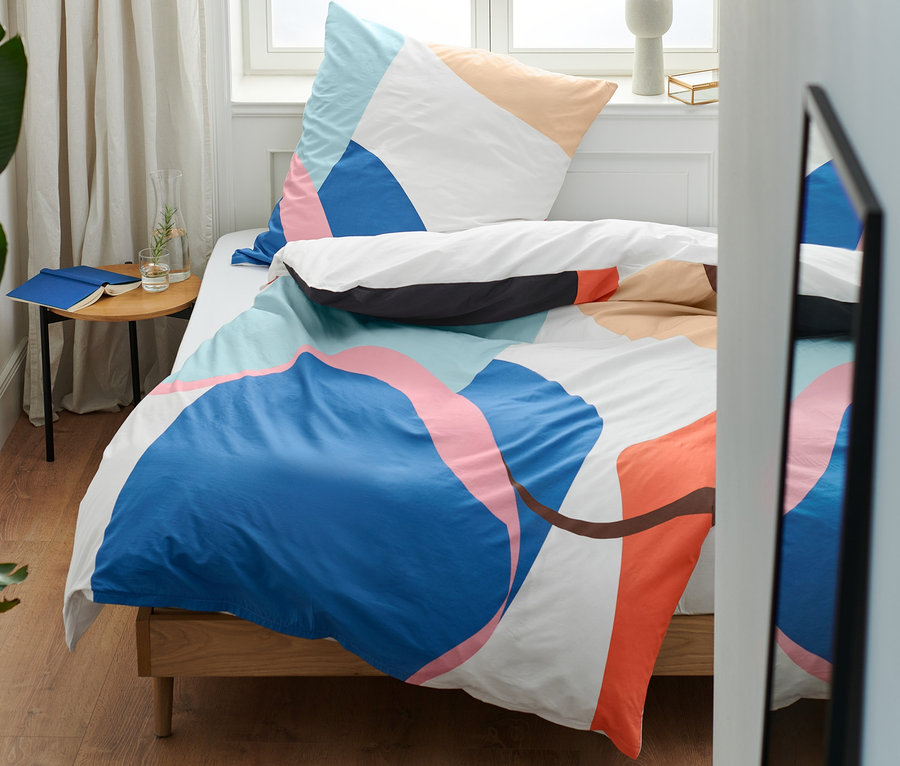 Bunte Premium-Baumwoll-Bettwäsche auf einem Bett in einem Schlafzimmer.