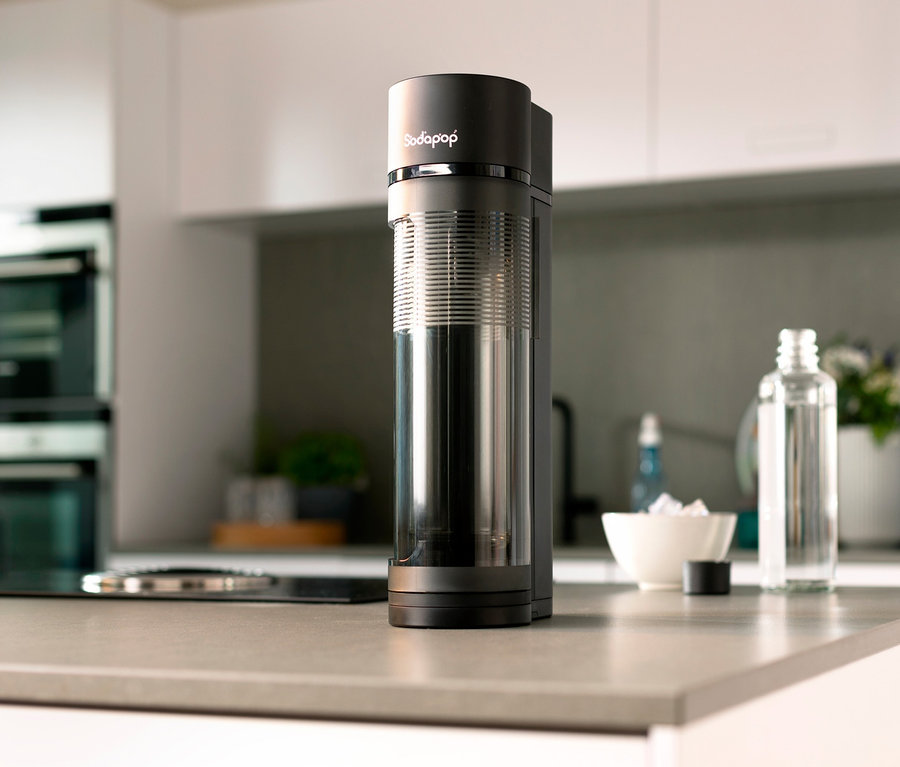 Auf einer Küchentheke steht ein Sodapop Wassersprudler »Logan« neben einer Glasflasche und einer Schale mit Eis.